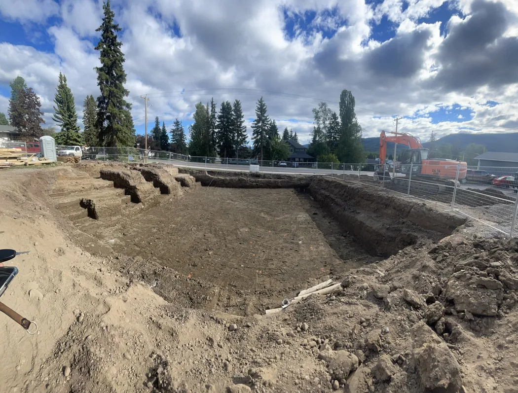 Large lot excavated and shaped for a new build with an excavator working the far edge